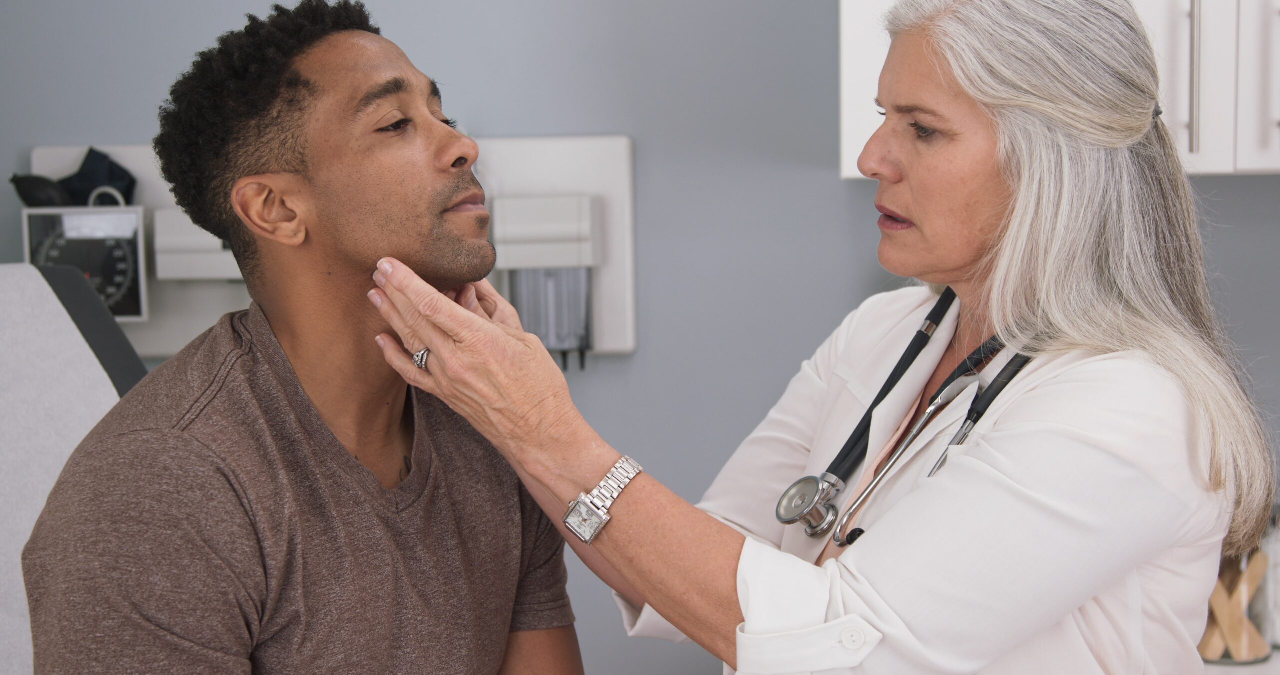 A female doctor checks the lymph nodes in the neck of a male patient.